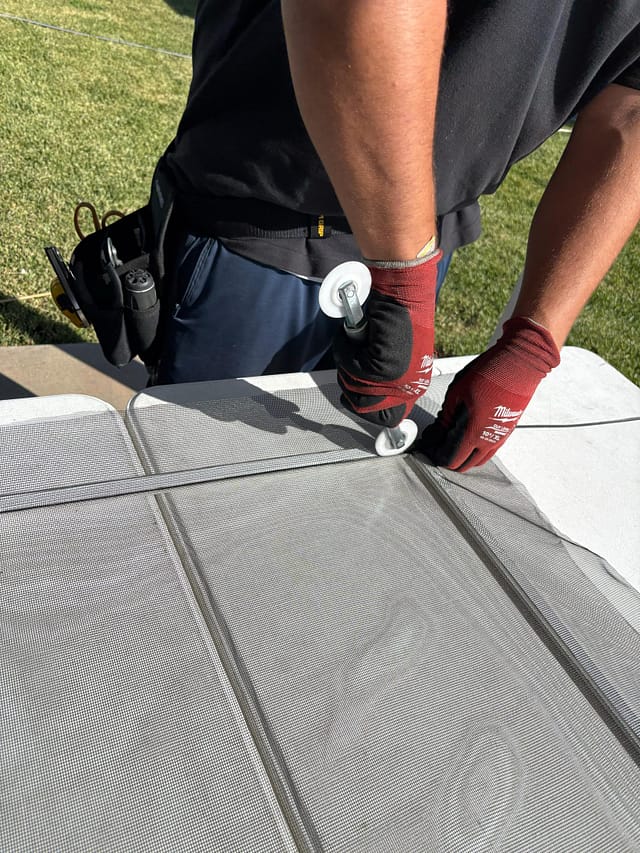 Technician re-screening a window screen with new mesh and spline in San Diego
