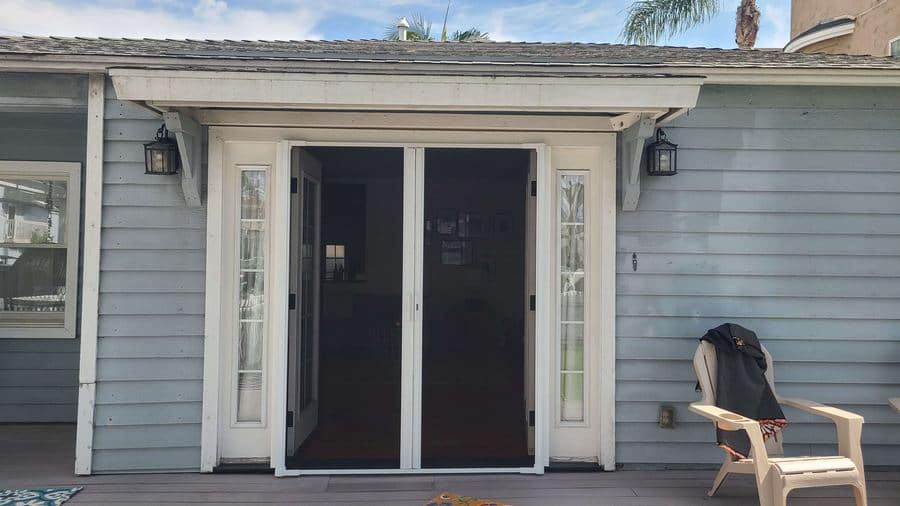 A double retractable screen pulled across a pair of white French doors on a covered patio