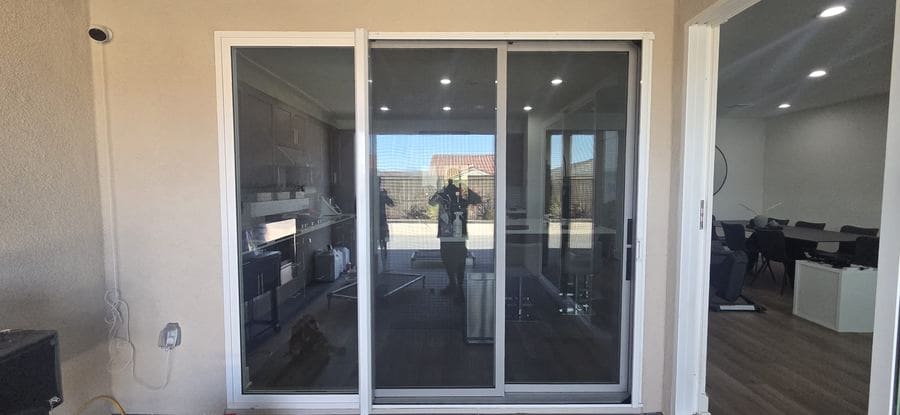 A retractable screen pulled across a wide sliding patio door at a large home
