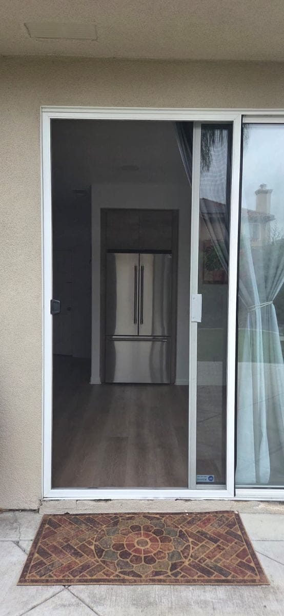 A white-framed sliding screen door closed across a patio slider at a Chula Vista home