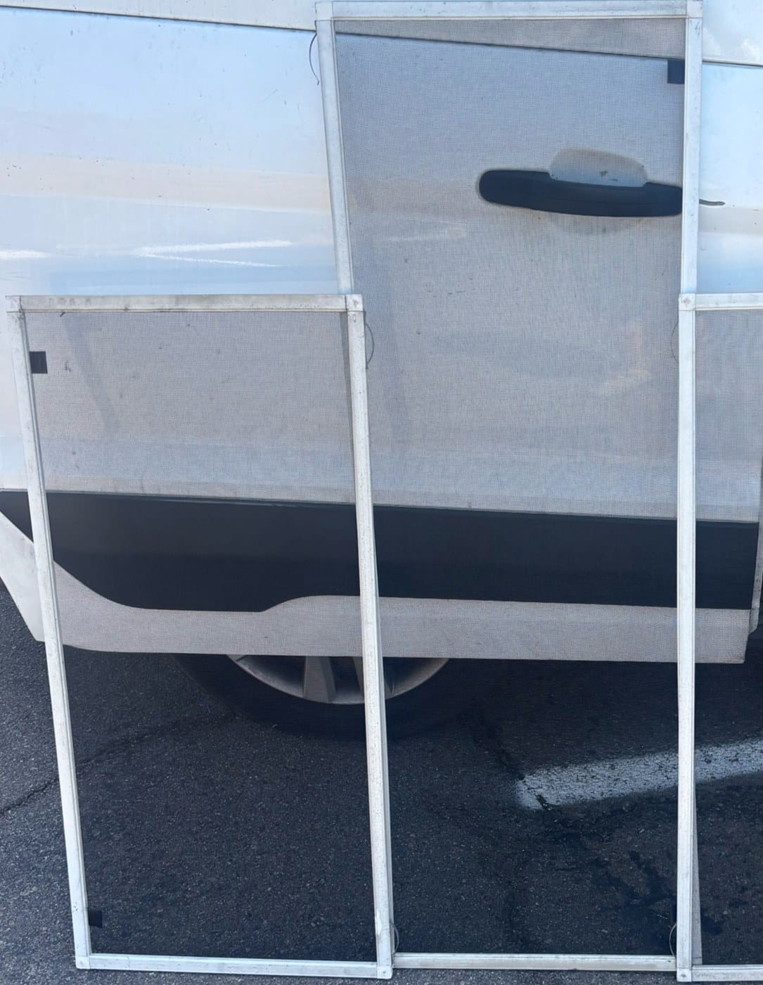 Window screen frames beside a service van.